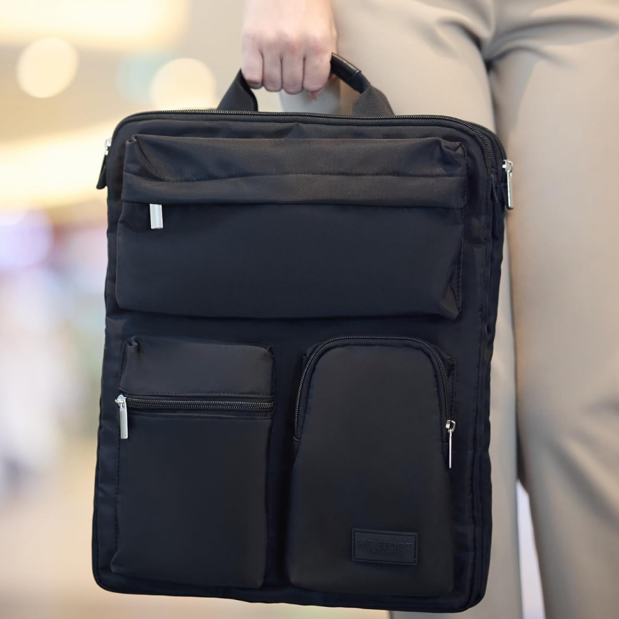 Traveler carrying the black luggage organizer bag by its top handle as a slim laptop and business bag